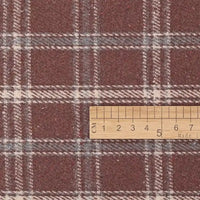 A wooden ruler, displaying centimeter measurements, is placed on Longan Craft’s Vintage Checked Mammoth Flannel Fabric by the yard—a thick cotton gingham flannelette in a maroon and white check pattern.