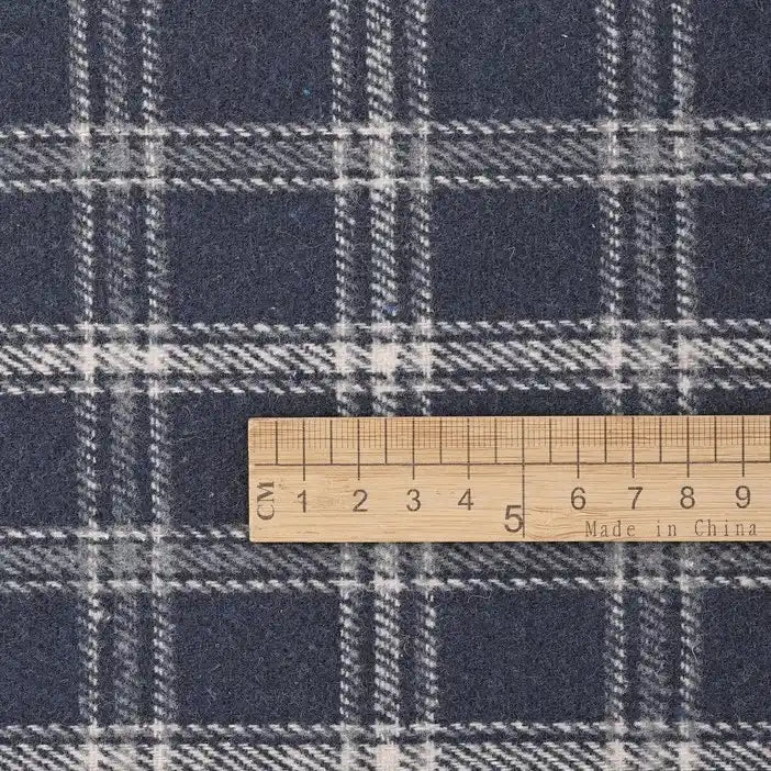 A wooden ruler marked in centimeters lies on Longan Craft’s Vintage Checked Mammoth Flannel Fabric, a thick cotton gingham flannelette with a soft white and gray plaid pattern, showing the scale from 0 to 10 centimeters.