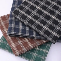 Four folded pieces of Longan Craft’s Vintage Checked Mammoth Flannel Fabric, a thick cotton gingham flannelette available in black, navy blue, brown, and green plaid patterns, are stacked on top of each other against a white background.
