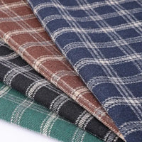Four pieces of Longan Craft Vintage Checked Mammoth Flannel Fabric are neatly stacked in blue, brown, black, and green—each featuring a distinct white gingham pattern. This thick cotton flannelette material is soft and brushed, making it perfect for cozy and durable fall sewing projects.