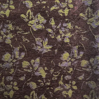 A close-up of Longan Craft’s Vintage Flower Pattern Chenille Fabric by the yard shows a brown background with abstract yellow and pale purple floral jacquard, featuring scattered, softly blurred flowers and leaves—ideal for home décor.