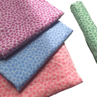 Four pieces of Longan Craft Watercolor Pebble Print Seersucker Fabric by the yard, made from 100% cotton and featuring a cozy leaf design in shades of pink, blue, and green, are neatly folded on a white background with an additional green roll placed separately.