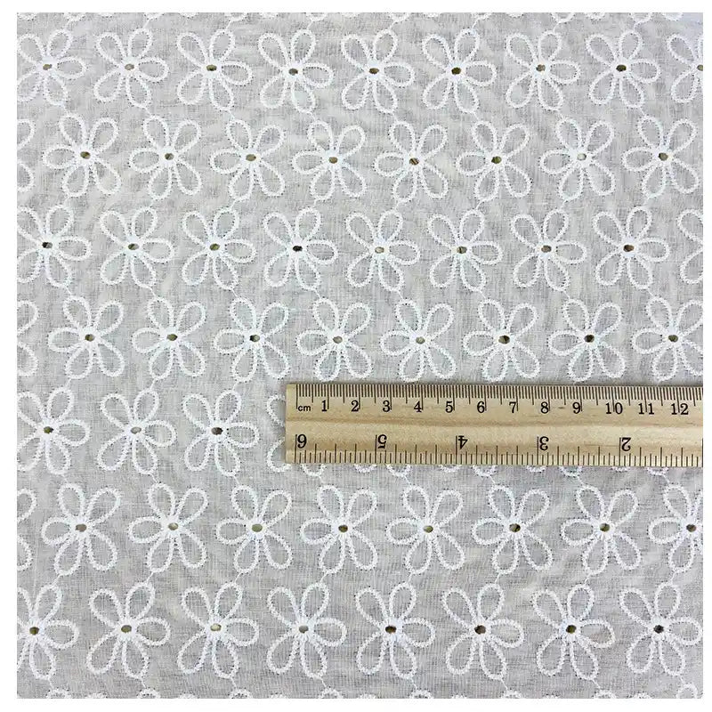 A square piece of Longan Craft White Floral Eyelet Embroidered Voile Fabric (100% cotton, hollow out embroidery) is shown with a ruler displaying both centimeters and inches for scale. Ideal for dressmaking and sewing projects.