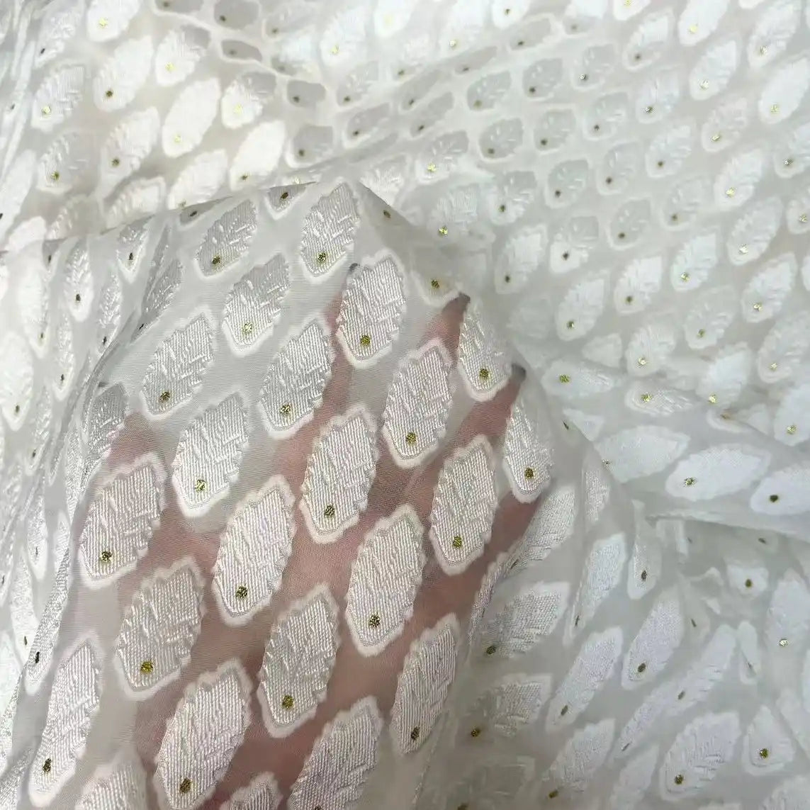 A hand is visible beneath Longan Craft’s White Leaf Pattern Organza Fabric, showcasing its translucent botanical jacquard design and delicate texture—ideal organza material for clothing by the yard.