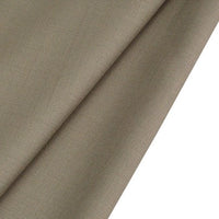 A close-up of Longan raft's Worsted Wool Gabardine Fabric By The Yard shows the smooth texture and subtle weave of this durable, poly-wool blended twill gabardine textile, ideal for tailored suits. Light brown fabric is folded diagonally.