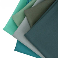 Five neatly stacked pieces of Longan raft Worsted Wool Gabardine Fabric in green and teal shades, displayed in a fan on white. Durable colorful poly wool twill gabardine—ideal for tailored suits, available by the yard.