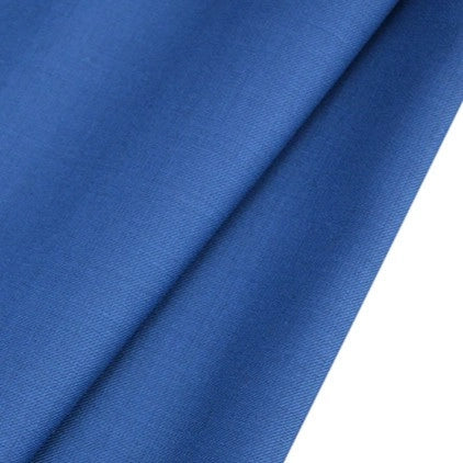 A close-up of Longan raft's Worsted Wool Gabardine Fabric shows its smooth, folded blue poly-wool blended twill with a soft texture and subtle shadows, perfect for durable, tailored suits by the yard.