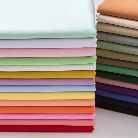 A stack of Longan Craft Woven Lawn Fabric By The Yard in multicolor solid shades—white, pink, yellow, green, orange, purple, blue, red, brown, and beige—shows off this soft cotton lawn lining material.