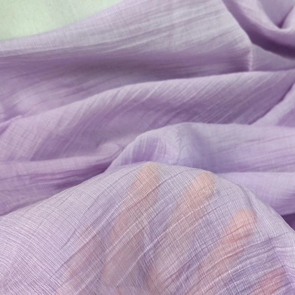 A hand is visible behind the Longan Craft Wrinkled Lyocell Fabric By The Yard, showing the solid color sustainable lyocell’s breathable translucency and soft, crinkled texture—ideal for making tops.