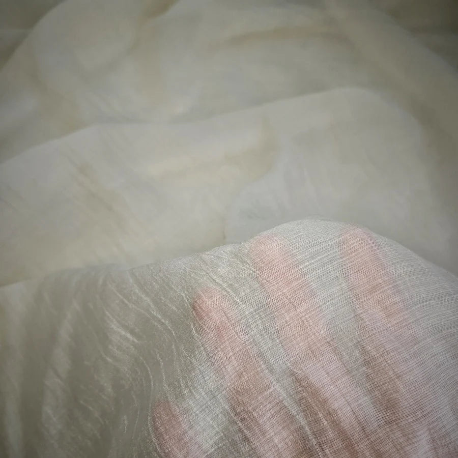 A hand beneath a layer of Longan Craft’s Wrinkled Lyocell Fabric By The Yard reveals the sustainable material’s translucency and delicate, breathable texture—ideal for crafting tops.