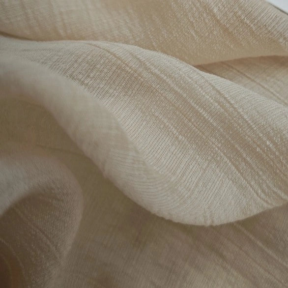 A close-up of Longan Craft’s Wrinkled Lyocell Fabric By The Yard shows its light beige, breathable, textured surface with gentle folds—ideal as a sustainable lyocell material for tops.