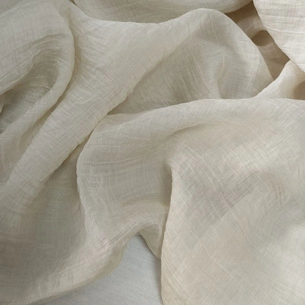 Longan Craft's Wrinkled Lyocell Fabric by the yard offers a cream-colored, lightweight, and semi-sheer sustainable material with a soft crinkled texture—perfect for creating breathable, elegant tops with gentle movement.