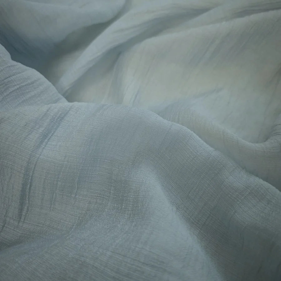 A close-up of Longan Craft's Wrinkled Lyocell Fabric By The Yard in light blue highlights its textured surface, soft folds, and breathable, sustainable appeal—perfect for tops.