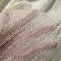 A hand is seen beneath Longan Craft’s Wrinkled Lyocell Fabric By The Yard, its fingers forming a subtle outline through the sheer, textured, sustainable lyocell material—perfect for breathable tops.