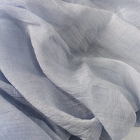 A close-up of Longan Craft’s Wrinkled Lyocell Fabric By The Yard reveals its light, sheer, and sustainable lyocell material with soft folds and a translucent texture in pale gray and white, ideal for breathable tops.
