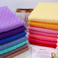 Two stacks of folded Sheer Swiss Dot Organza Fabric By The Yard featuring colorful 3D dots in shades of purple, blue, yellow, and pink.