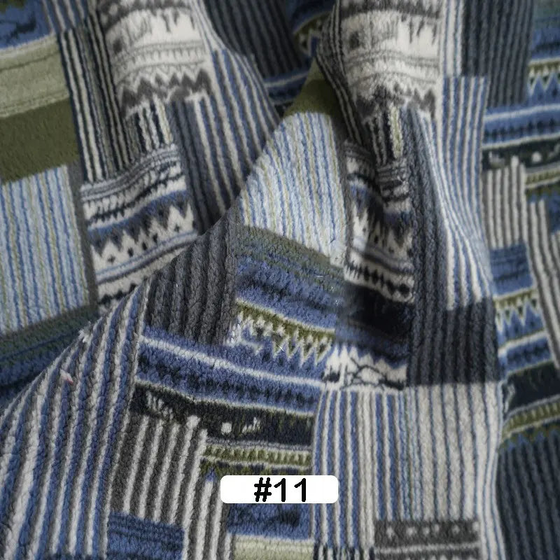 A close-up of Longon Craft’s Christmas Polar Fleece Fabric By The Yard, a thick, double-sided polyester with a blue, gray, white, and green patchwork print. The bottom features a white label marked #11 in black.