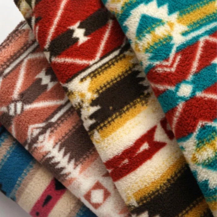 Four vibrant, folded Longon Craft Christmas Polar Fleece Fabric by the yard, featuring bold tribal and geometric prints in red, turquoise, yellow, black, and beige—ideal for festive, cozy creations with double-sided, thick polyester material.