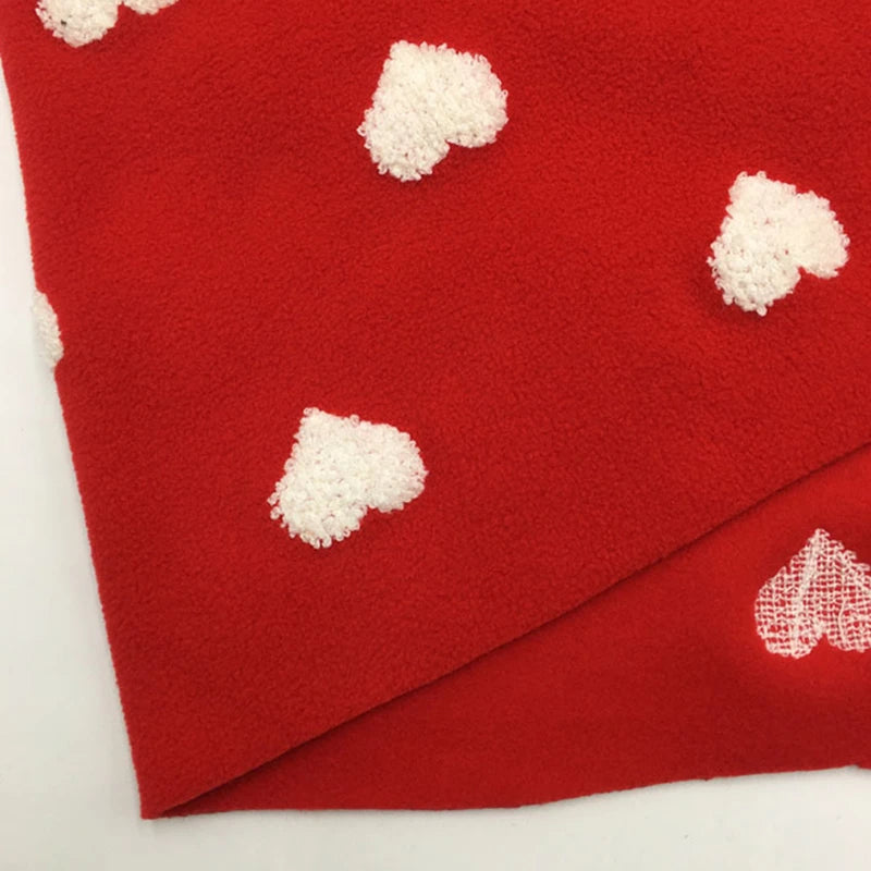 A yard of Longon Craft’s Heart Polar Fleece Fabric, featuring a 3D white heart pattern on red, made from cozy polyester—perfect for sewing and crafts. One corner is folded to show the soft underside with a single heart.