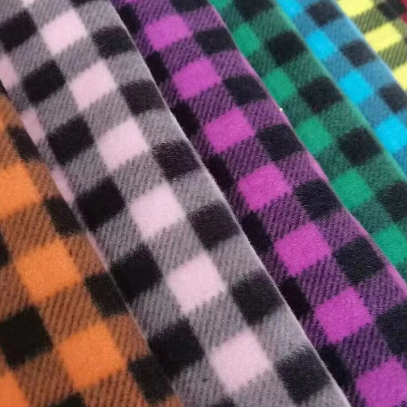 Diagonal rolls of vibrant plaid polar fleece from Longon Craft, featuring orange, green, and blue checks. This 100% polyester fabric is perfect for warm, stylish DIY sewing projects. Available by the yard—ideal for cozy creations.