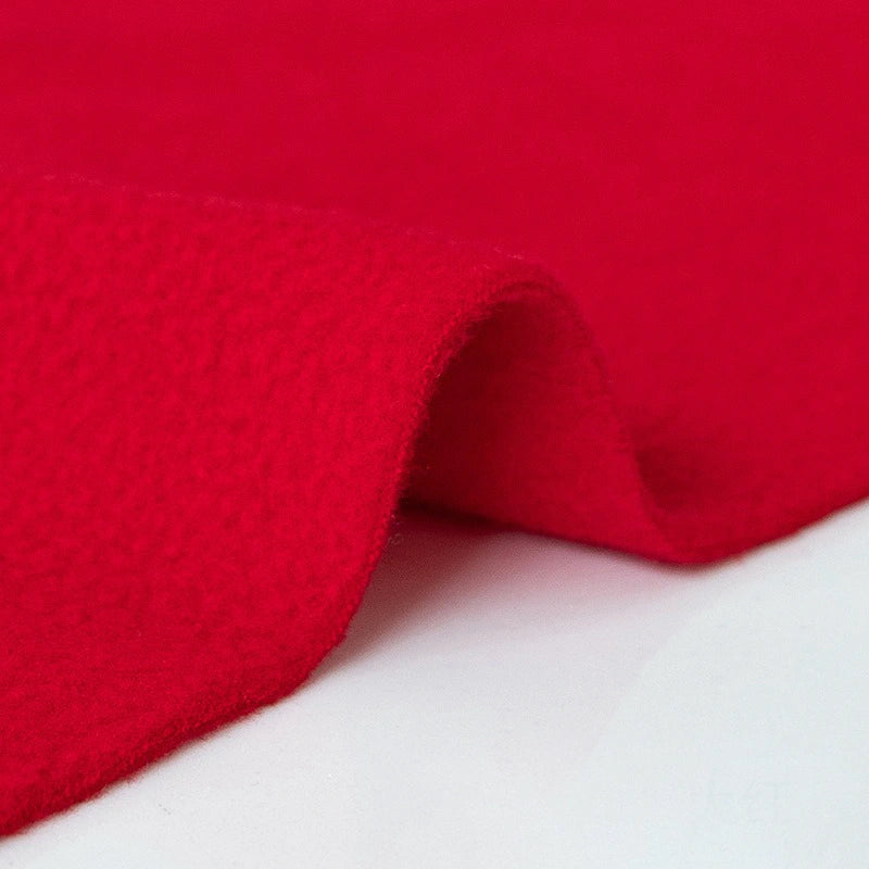 Close-up of Longon Craft’s Plain Polar Fleece Fabric by the yard—thick, anti-pill polyester with a soft, fuzzy texture—gently folded on a white surface to display its flexible stretch and vibrant red color.