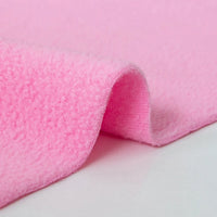 Close-up of Longon Craft Plain Polar Fleece Fabric By The Yard, a thick polyester anti-pill material in light pink, with a soft, textured surface, slightly folded and displayed on a smooth white background.