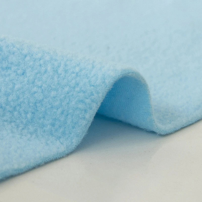 A close-up of Longon Craft's Plain Polar Fleece Fabric By The Yard highlights its thick, anti-pill, light blue polyester material with a soft, textured surface and gentle fold—perfect for outdoor jackets or cozy thermal blankets.