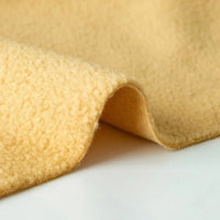 A close-up of Longon Craft's Plain Polar Fleece Fabric by the Yard shows its thick, anti-pill, light yellow polyester with a soft, textured surface—ideal for sewing cozy outdoor jackets and crafts.