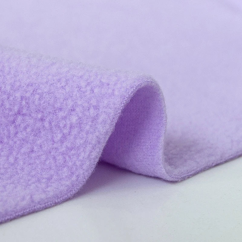 A close-up of Longon Craft’s Plain Polar Fleece Fabric by the Yard, a thick, anti-pill, light purple polyester material with stretch, folded to show texture and thickness, ideal for thermal blankets and outdoor jackets, on a white background.