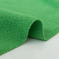 A close-up of Longon Craft's Plain Polar Fleece Fabric By The Yard shows its bright green, thick, anti-pill polyester surface as it curves on a white background—ideal stretch material for sewing outdoor jackets and thermal blankets.
