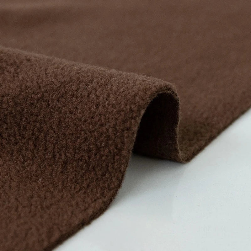 A close-up of Longon Craft's Plain Polar Fleece Fabric By The Yard highlights its thick, soft, anti-pill polyester surface. This stretch sewing material is partially folded in gentle curves against a smooth white background.