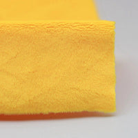 A close-up of plush yellow Minky fabric by Longon Craft, made from ultra-soft 5mm polyester, folded neatly on a light gray surface—perfect for sewing plushies and crafts.