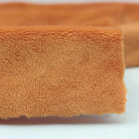 Close-up of Longon Craft Plush Minky Fabric By The Yard (5mm soft polyester, solid orange) on a white surface—ideal for baby blankets, plushies, and craft sewing projects.