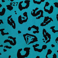 A turquoise Printed Polar Fleece Fabric by the yard from Longon Craft with a black ethnic leopard pattern. #27 is in black text at the top left. Ideal for DIY craft and sewing projects.