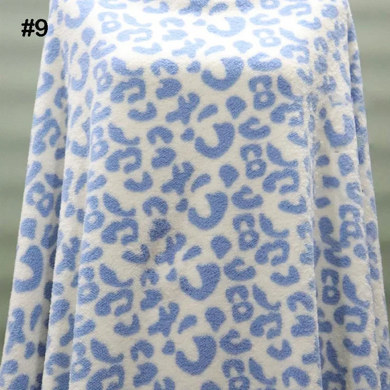 A piece of Longon Craft's Printed Polar Fleece Fabric By The Yard, featuring a blue ethnic leopard pattern, covers an object with a corner folded. The white, soft polyester fabric has a number 9 in the top left corner.