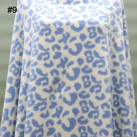 A piece of Longon Craft's Printed Polar Fleece Fabric By The Yard, featuring a blue ethnic leopard pattern, covers an object with a corner folded. The white, soft polyester fabric has a number 9 in the top left corner.