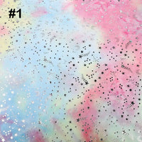 Rainbow Minky Fabric by Longon Craft features a pastel tie-dye background in pink, blue, and yellow with scattered silver and black stars—perfect for plushies, crafts, or sewing. "#1" is labeled in the top left corner.