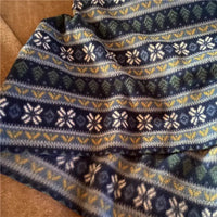 A close-up of Longon Craft’s Snowflake Polar Fleece Fabric By The Yard, featuring a blue stripe patterned print with white, green, and yellow geometric and snowflake designs—ideal polyester fleece for DIY sewing crafts.