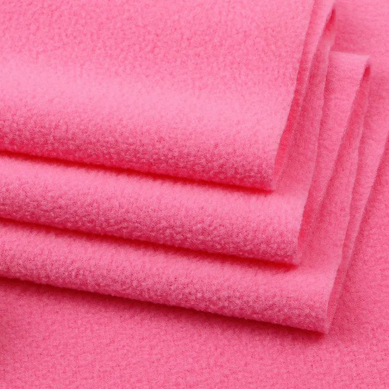 Neatly stacked bright pink Solid Polar Fleece Fabric by Longon Craft shows its thick, soft surface—ideal for cozy blankets or DIY sewing. Buy this 100% polyester material by the yard for your next craft or upholstery project.