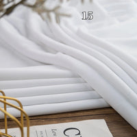 A stack of Longon Craft Stretch Minky Fabric By The Yard (Multicolor Four Way Stretch) is neatly folded on a wooden surface marked with the number 15. A magazine and gold wire accessory are partially seen in the background.