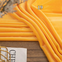 A folded piece of bright yellow Stretch Minky Fabric by Longon Craft, labeled "19", is displayed on a wooden surface next to a partially visible magazine.