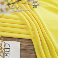 A stack of Longon Craft Stretch Minky Fabric By The Yard lies on a wooden surface, partially framed by a magazine and plant. Number 21 is overlaid—ideal for baby blankets, cozy clothing, plushies, and DIY projects.