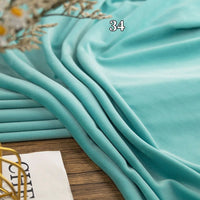A close-up of Longon Craft’s multicolor four-way stretch minky fabric by the yard, draped in light blue—ideal for DIY clothing, plushies, dolls, or baby blankets. Magazine and basket add a cozy touch; number 34 appears above.