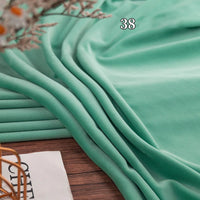 Longon Craft's Stretch Minky Fabric By The Yard—multicolor, four-way stretch cuddle minky—draped in folds on wood with a "38" overhead and a magazine and plant nearby; ideal for DIY clothing, plushies, dolls, pillows, and blankets.