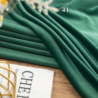 Longon Craft Stretch Minky Fabric By The Yard in multicolor is draped on a wooden surface, with part of a newspaper and the number "41" seen in the upper right corner. Perfect for DIY clothing, pillow plushies, and dolls.