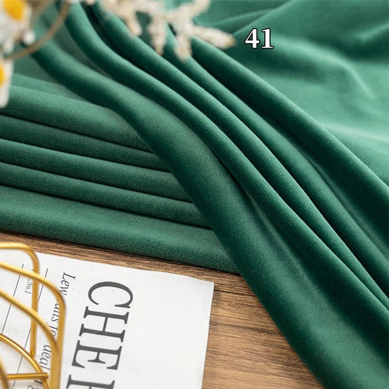 Longon Craft Stretch Minky Fabric By The Yard in multicolor is draped on a wooden surface, with part of a newspaper and the number "41" seen in the upper right corner. Perfect for DIY clothing, pillow plushies, and dolls.