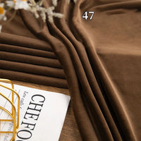 A piece of Longon Craft Stretch Minky Fabric by the yard, a multicolor four-way stretch cuddle material for DIY crafts, is draped and folded on a surface beside an open magazine and a decorative gold wire object.