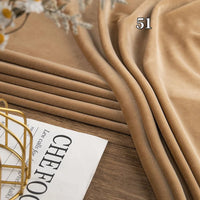 Several folded pieces of Longon Craft Stretch Minky Fabric in light brown are stacked on a wooden surface next to a "CHEFOOD" magazine. The number 51 appears on the fabric. Ideal for DIY clothing, pillows, plushies, and dolls.