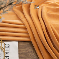 Longon Craft's Stretch Minky Fabric By The Yard in multicolor is draped on wood with "54" on top; a magazine peeks from the bottom left, perfect for DIY clothing, pillows, plushies, and dolls.