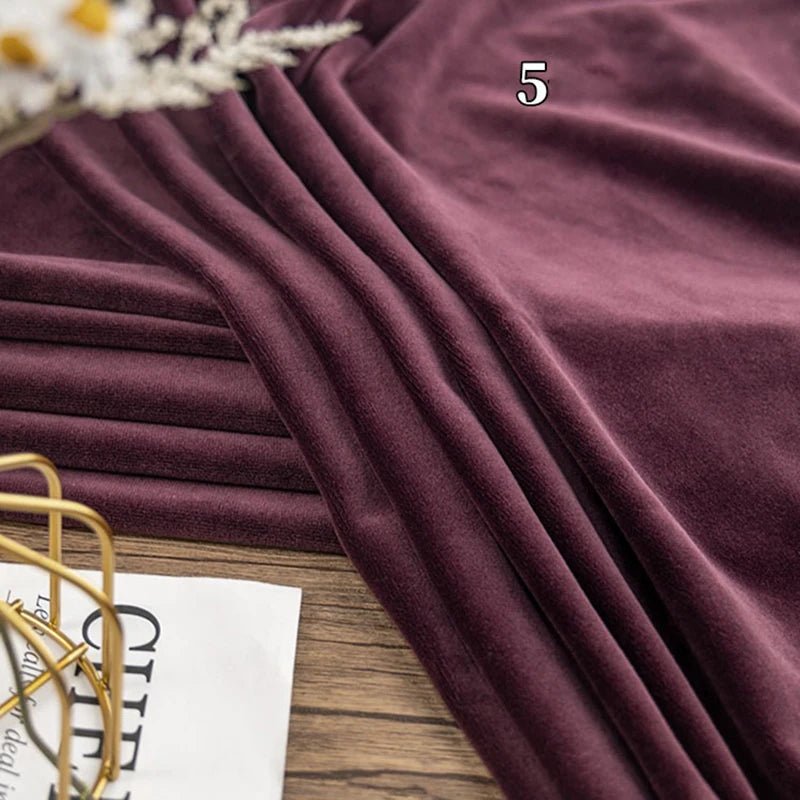 A piece of folded Longon Craft Stretch Minky Fabric By The Yard (Multicolor Four Way Stretch Cuddle) is shown on a wooden surface, with a number 5 above it and part of printed paper in the bottom left corner.